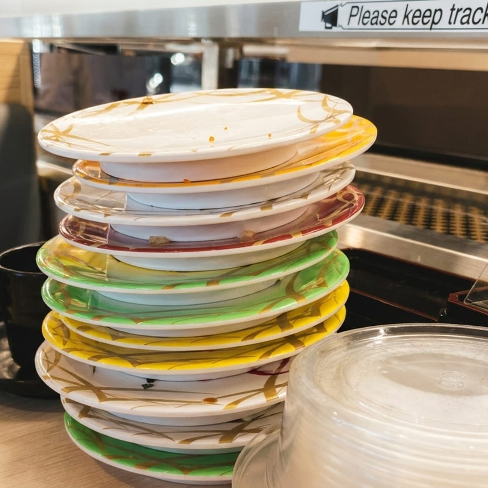 A tall stack of colorful, empty sushi plates on a counter at Tamago Sushi.